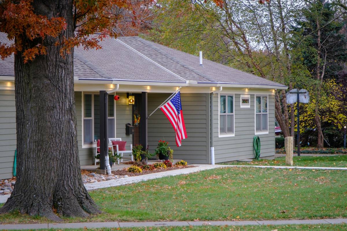 A single-storey neighborhood home with a United States flag flying on the front porch